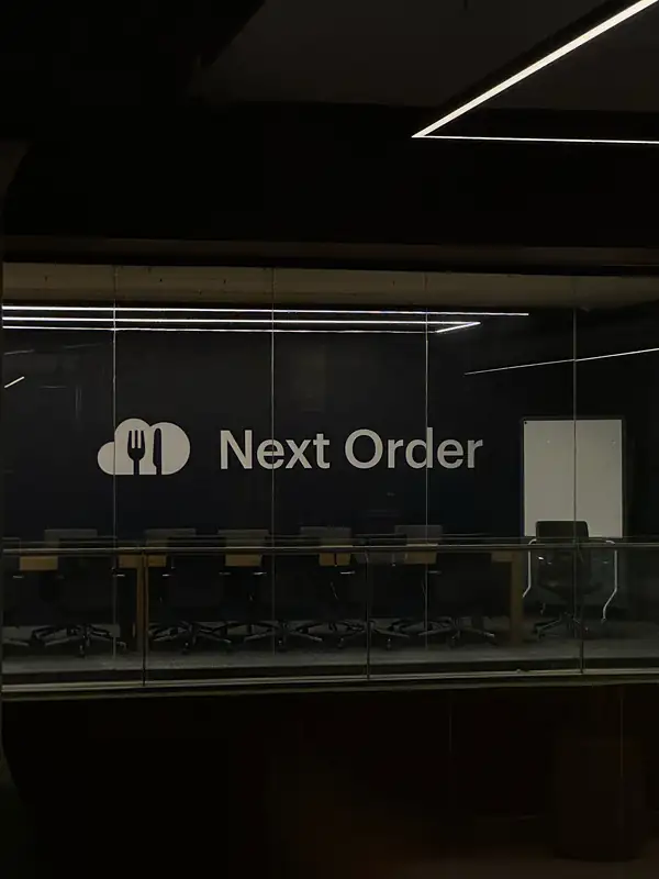 The glass walled boardroom, with the Next Order logo on its back wall.