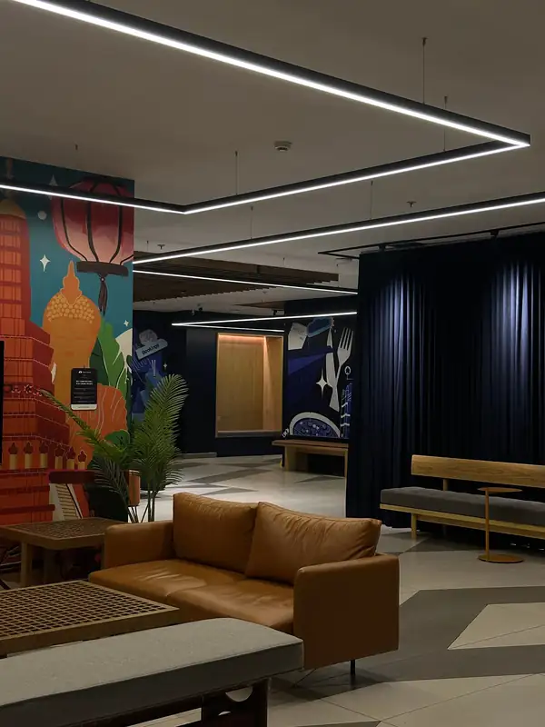 A breakout lounge with a leather sofa in front of a colourful mural of a Thai temple and lantern.