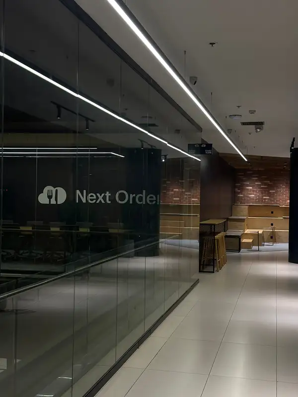 A corridor along the boardroom’s glass wall, leading to timber steps against a brick wall.