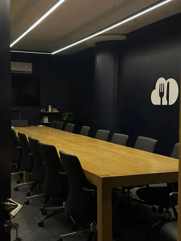 A meeting room with a long timber table, black chairs and the Next Order cloud on the wall.