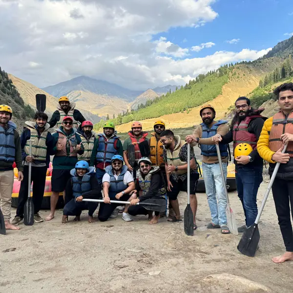 The team in helmets and life jackets holding paddles before going white water rafting.